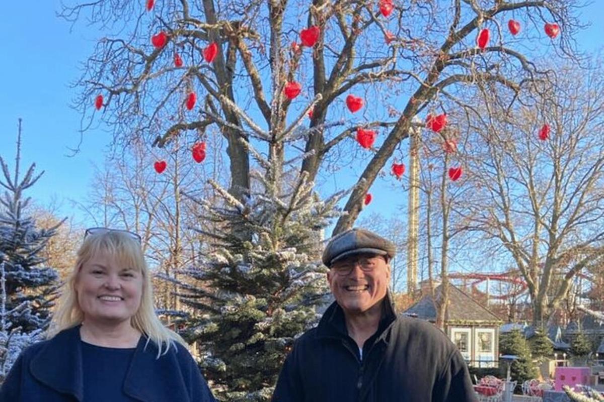 a man and a woman standing in front of a christmas tree