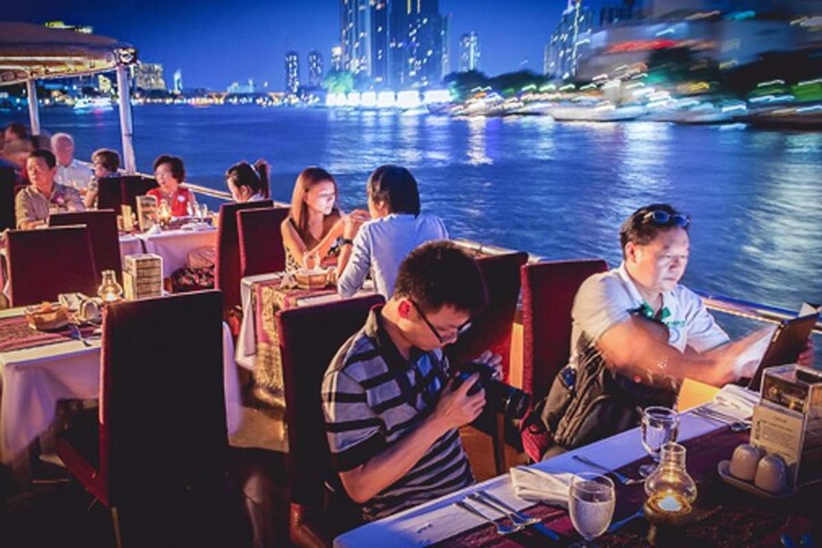 en gruppe mennesker sidder ved borde i en restaurant ved vandet