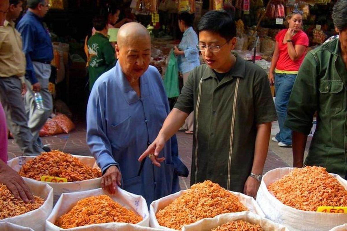 due uomini in piedi in un mercato con un sacco di cibo