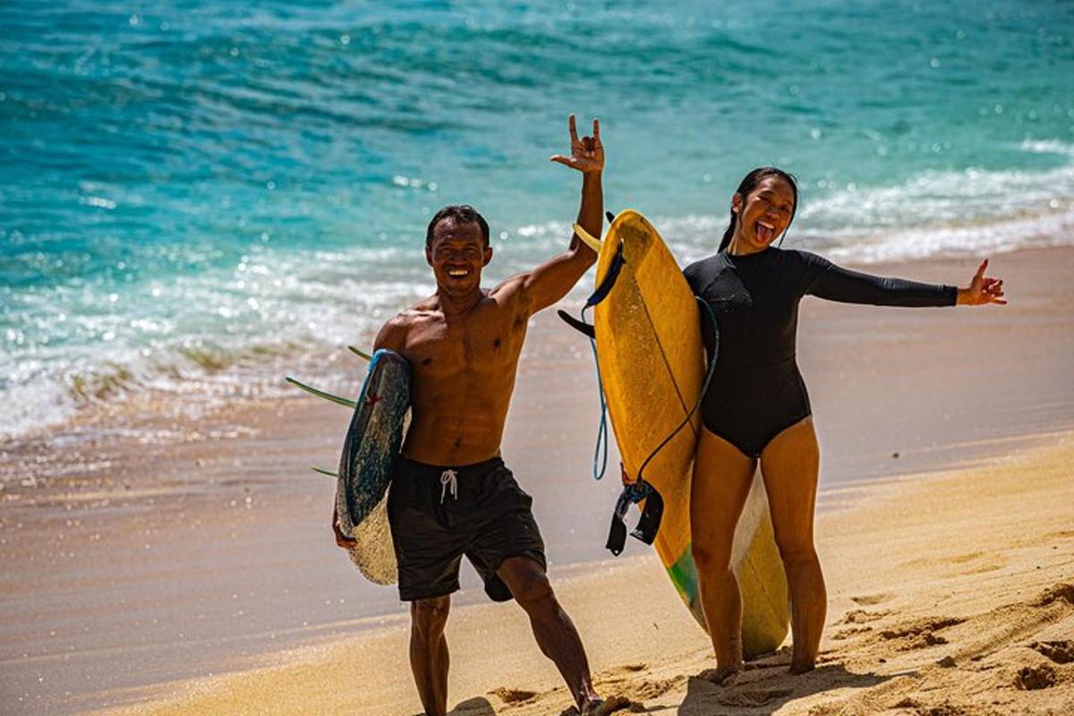 two people walking on the beach with their surfboards