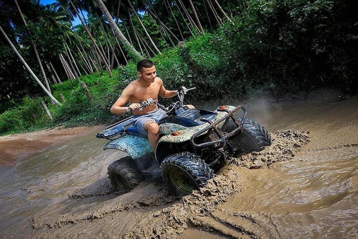 seorang lelaki menaiki atv melalui lumpur