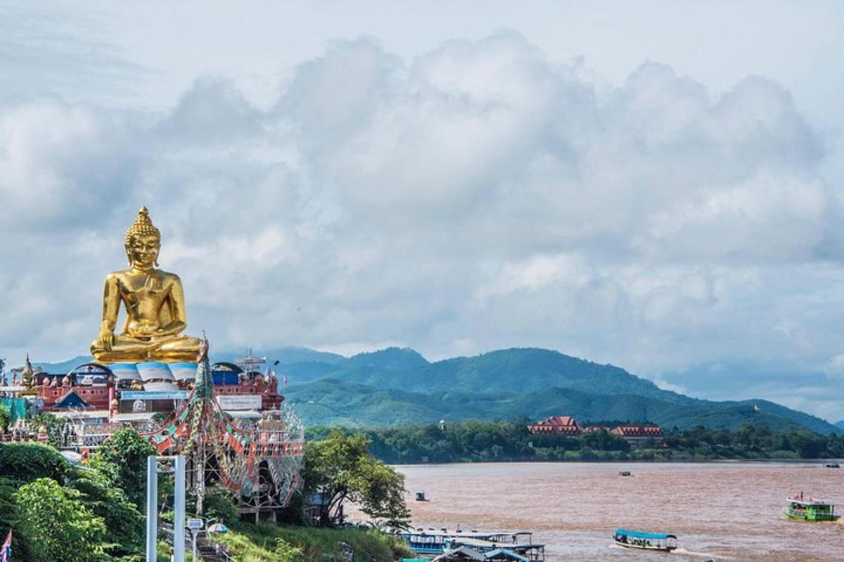 una grande statua dorata seduta sulla riva di un fiume