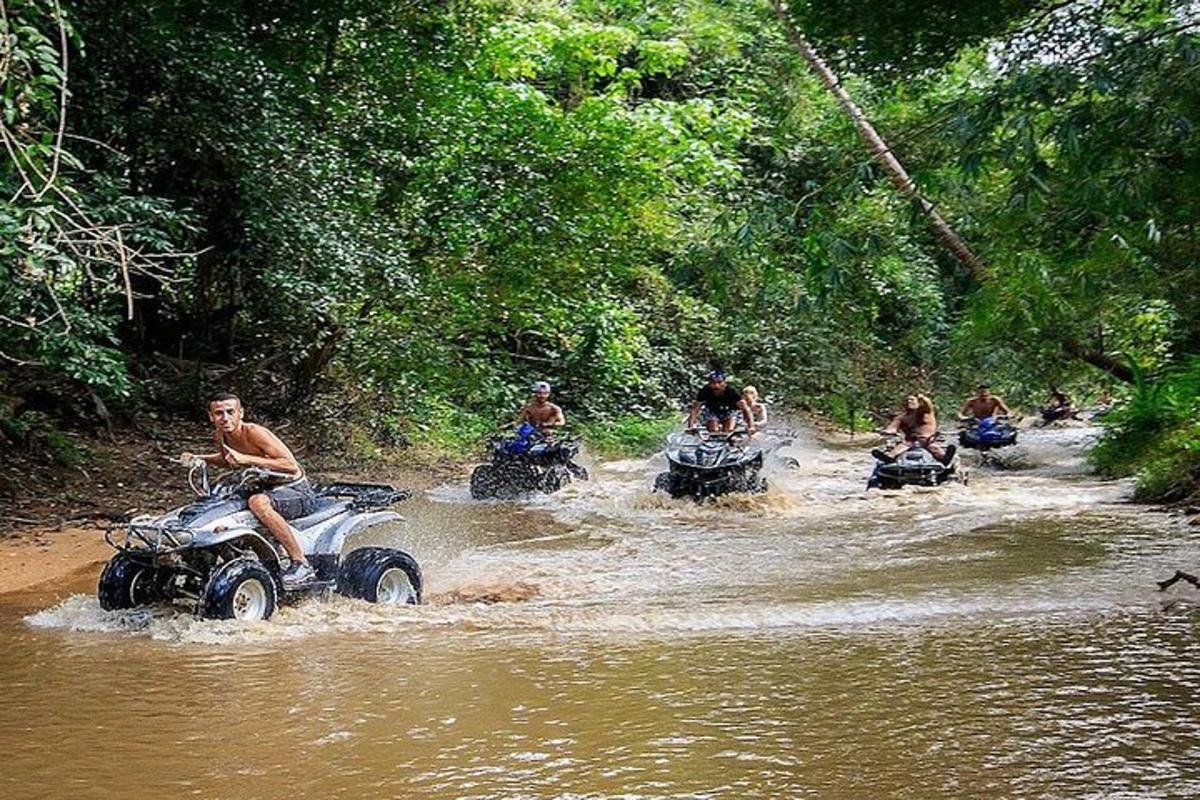 sekumpulan orang menunggang atv melalui sungai