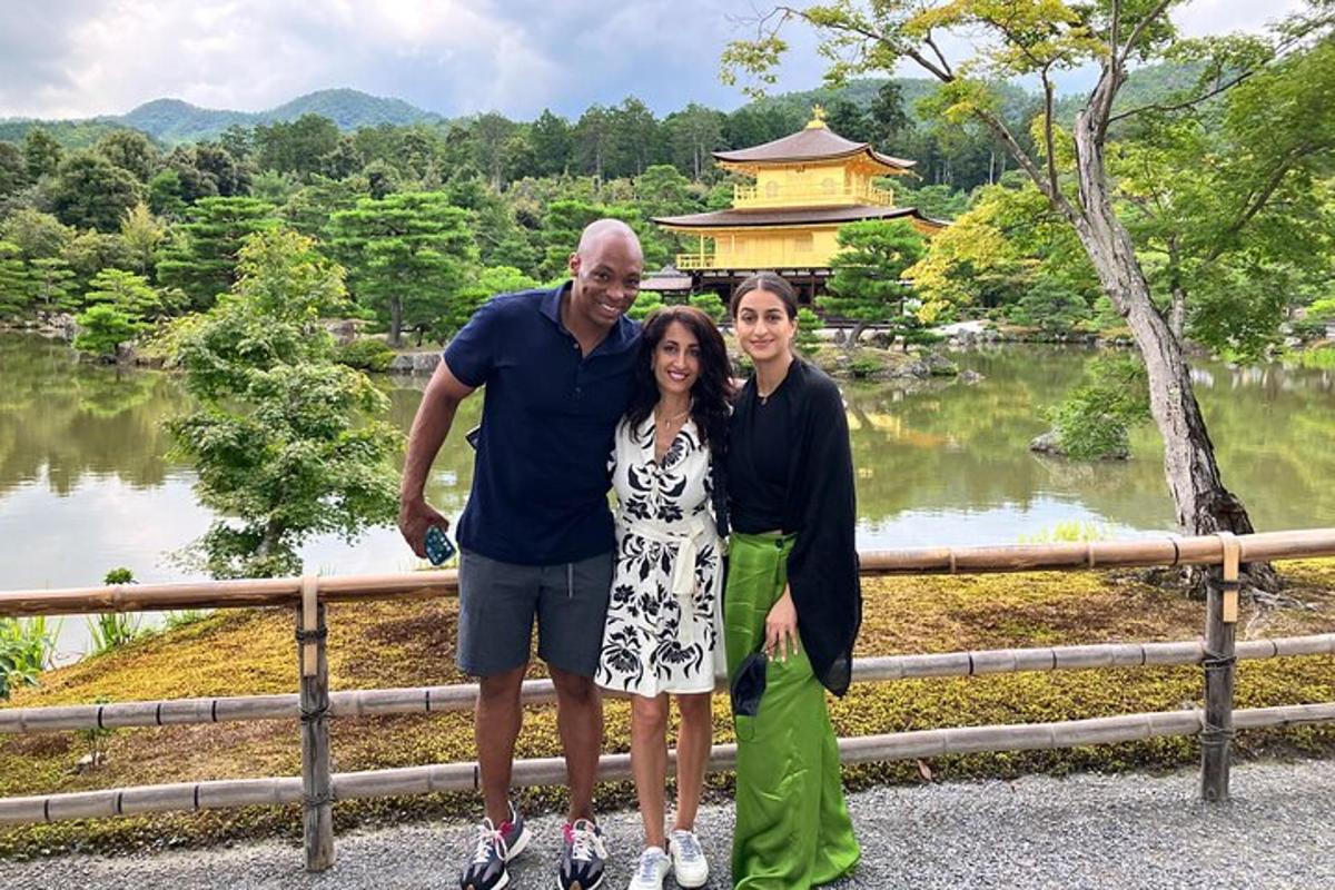 um homem e duas mulheres posando para uma foto em frente a um templo