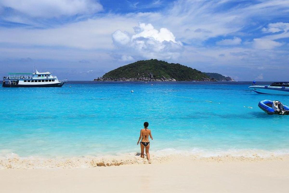 moški, ki stoji na plaži s čolnom v vodi