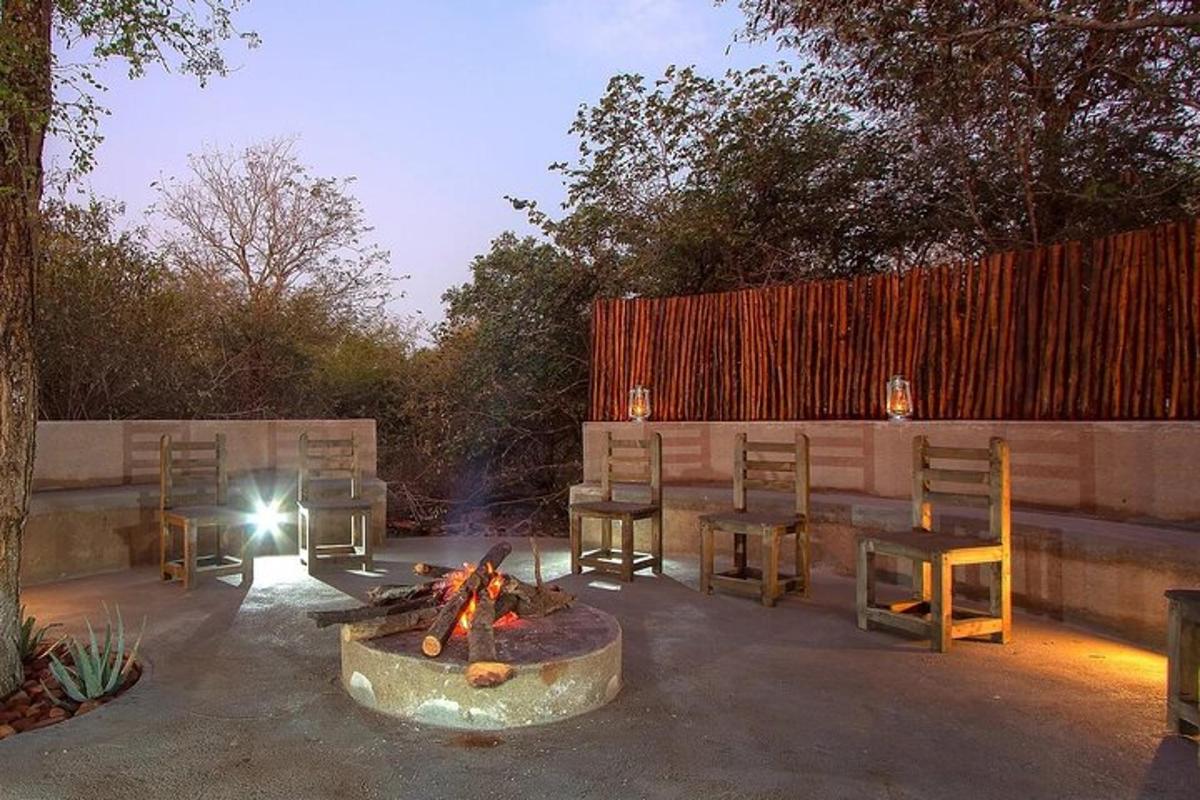 a patio with a fire pit and chairs and a fence