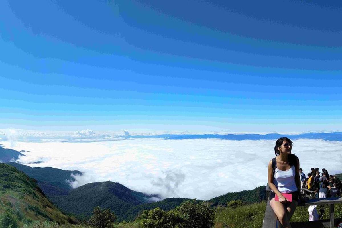Una mujer parada en la cima de una montaña con nubes.