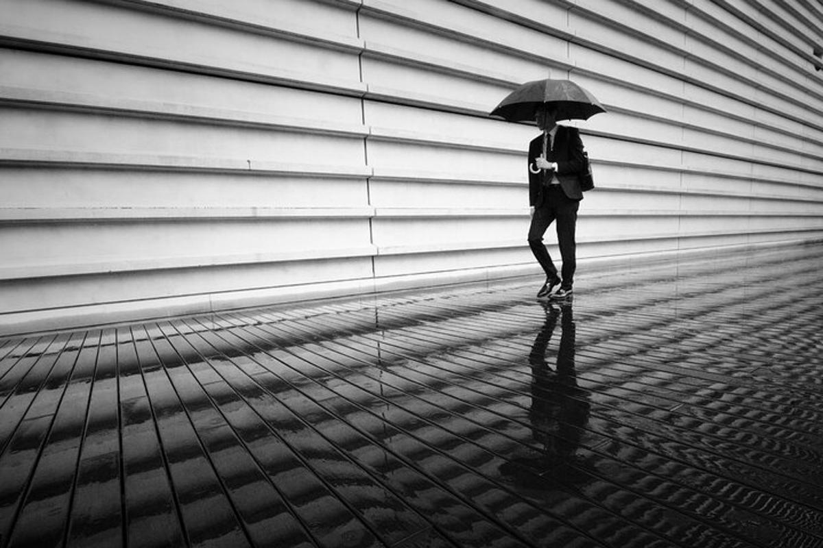 a woman walking down a sidewalk with an umbrella