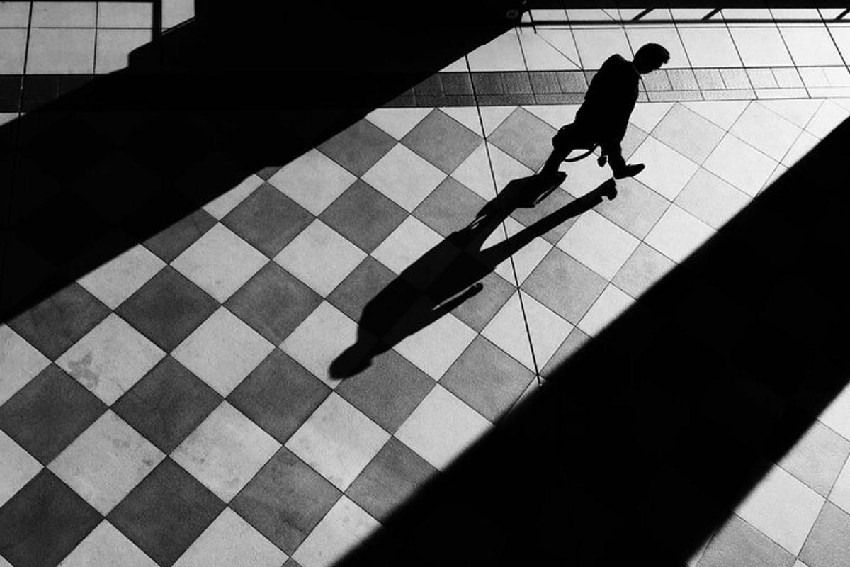 Un hombre montando una patineta en un suelo cuadriculado