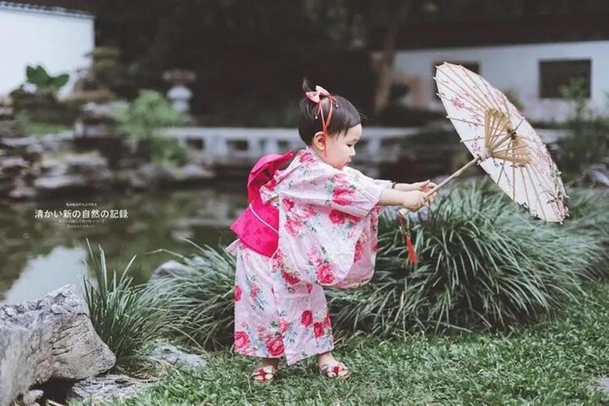 uma menina de quimono segurando um guarda-chuva