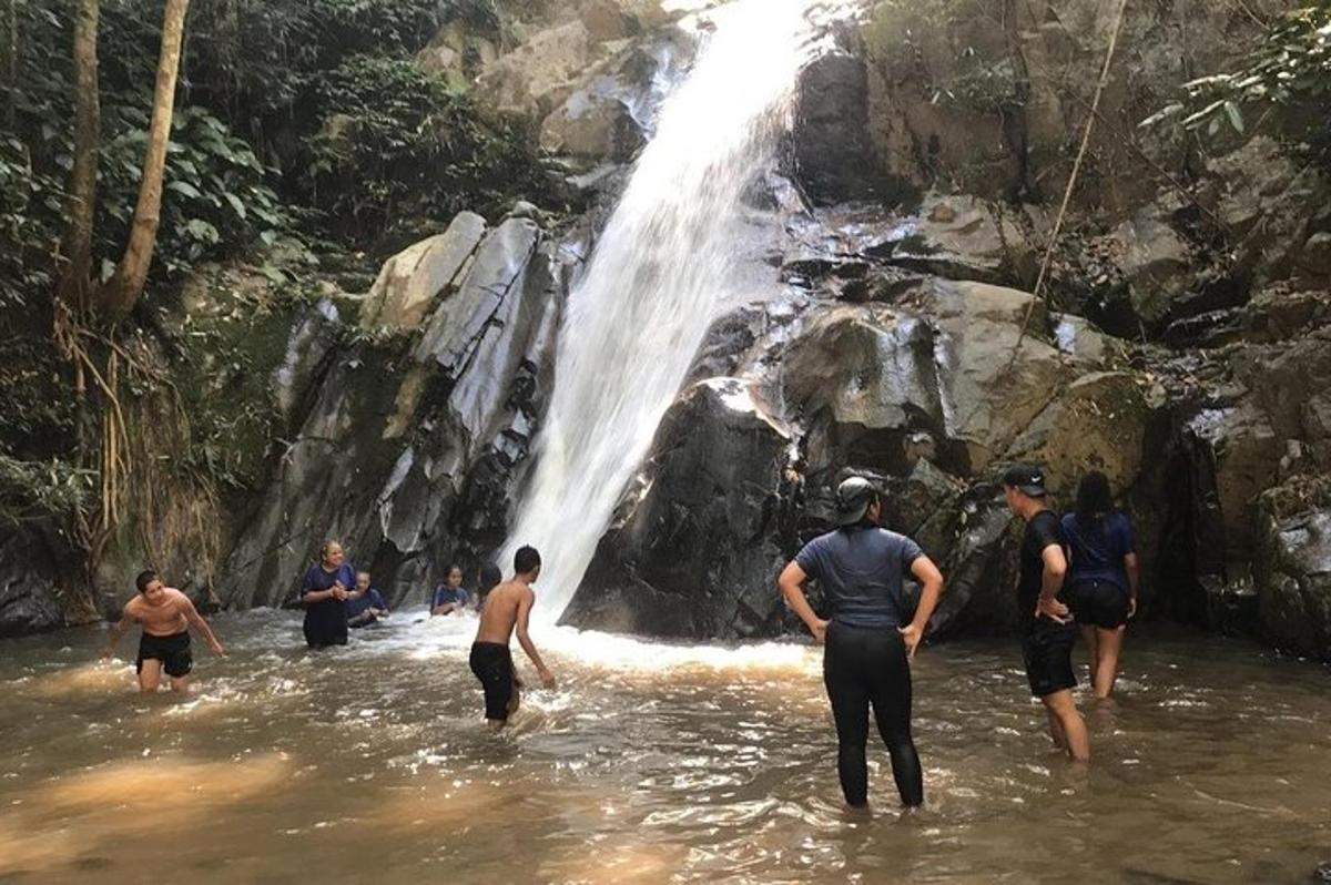 un gruppo di persone che camminano nell'acqua vicino a una cascata