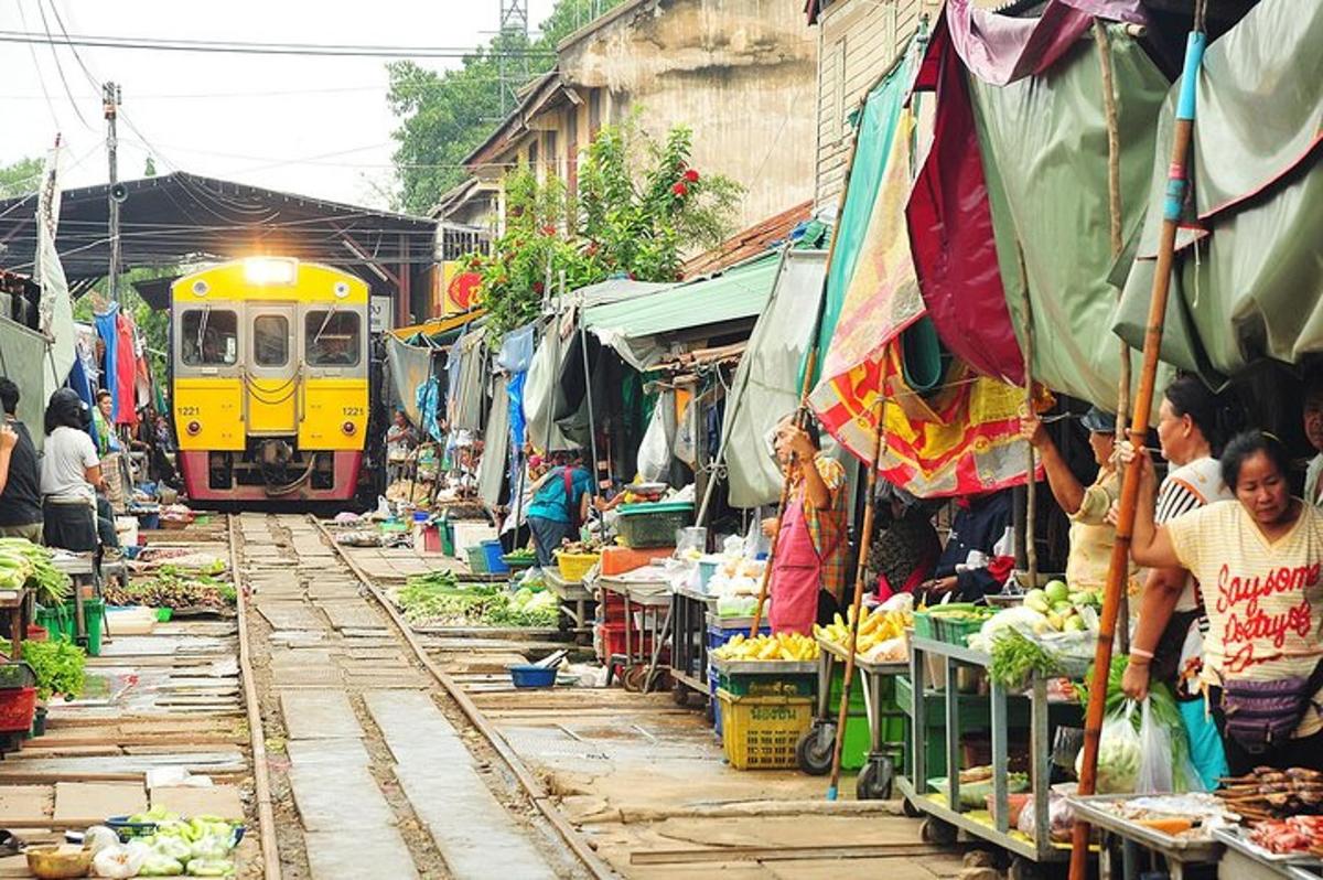 kereta api sedang melalui pasar dengan orang dan sayur-sayuran