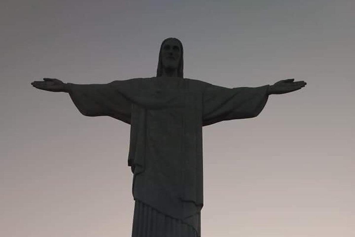 un uomo in piedi sulla statua del Cristo Redentore