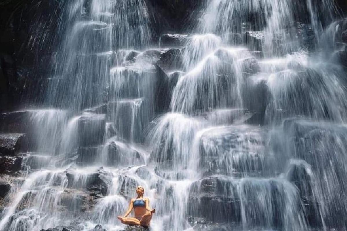 a woman sitting in front of a waterfall