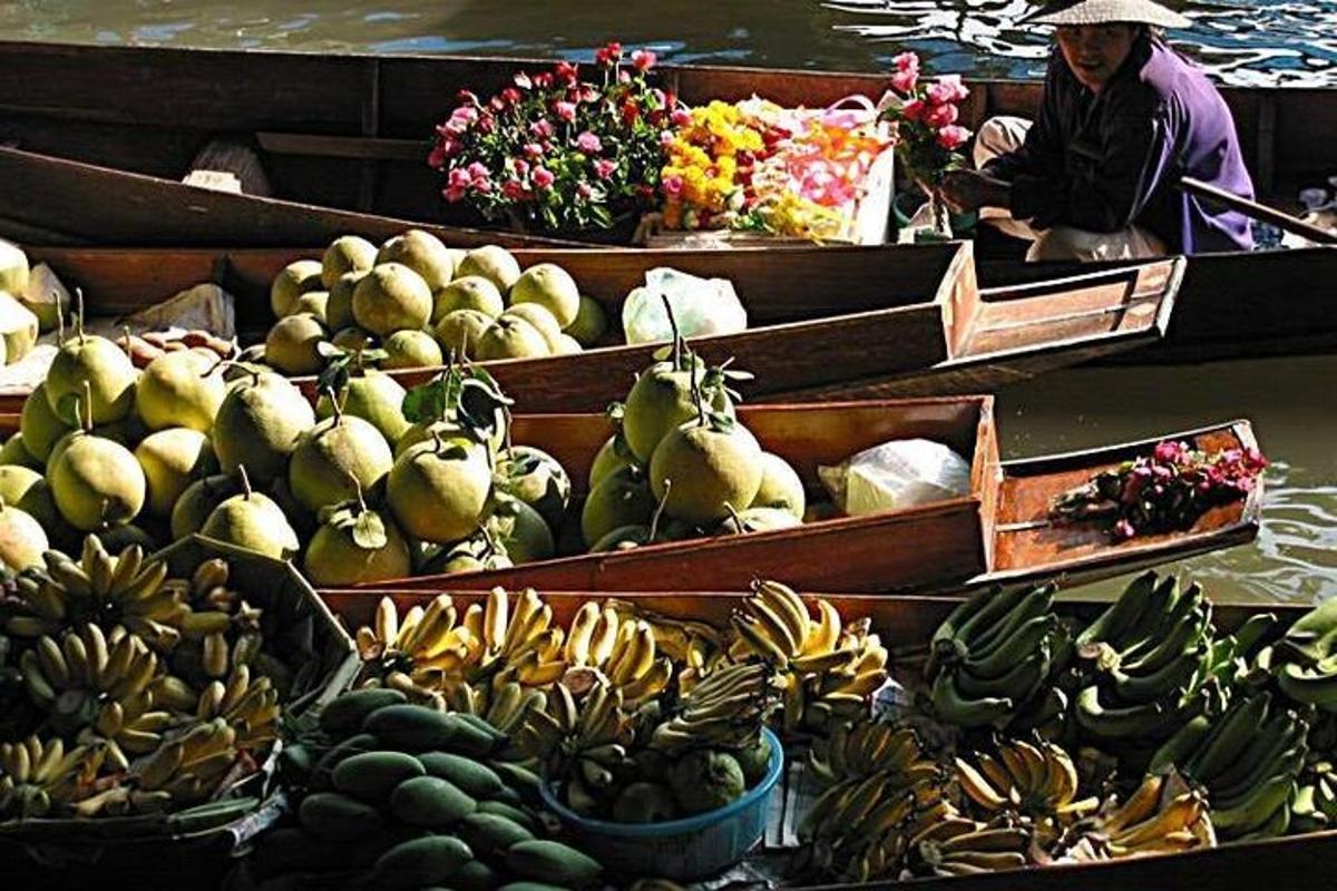 una donna su una barca piena di frutta e verdura