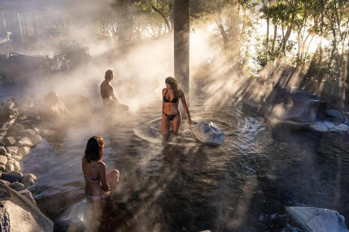 a group of people standing in a hot spring with steam
