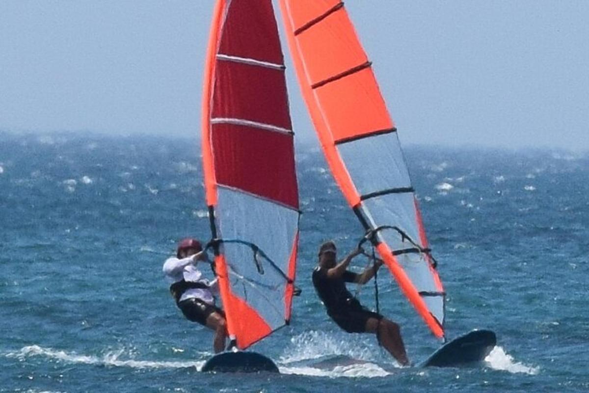 dva lidé windsurfují v oceánu na vodě