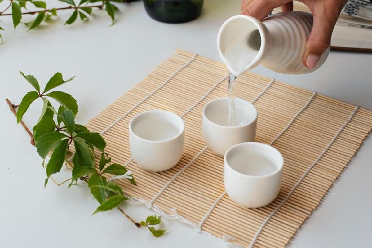 Una persona sirviendo café en tres tazas sobre una tabla de cortar de bambú.