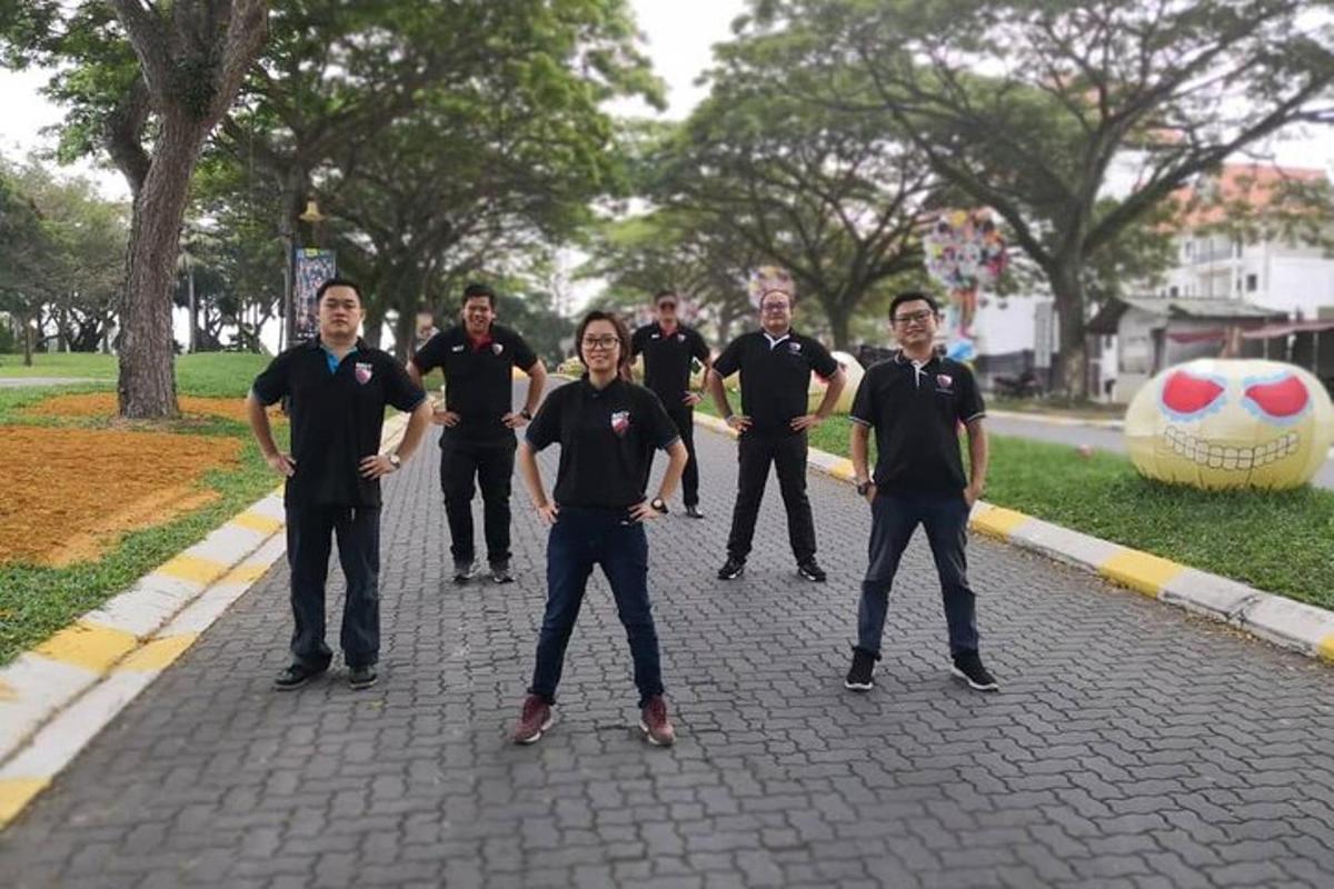 a group of men in black shirts standing in a park