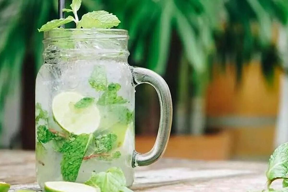 một lọ thủy tinh chứa đầy nước với bông cải xanh và dưa chuột