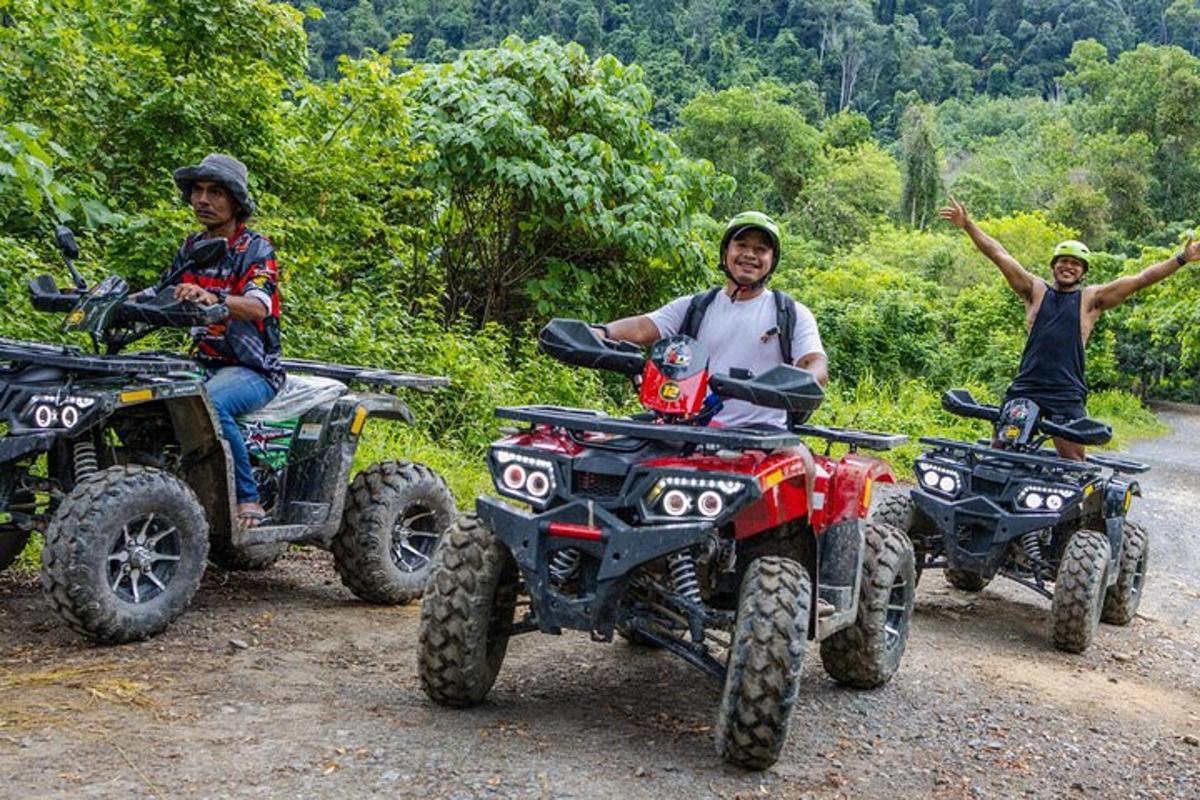 três pessoas sentadas em quadriciclos em uma estrada de terra