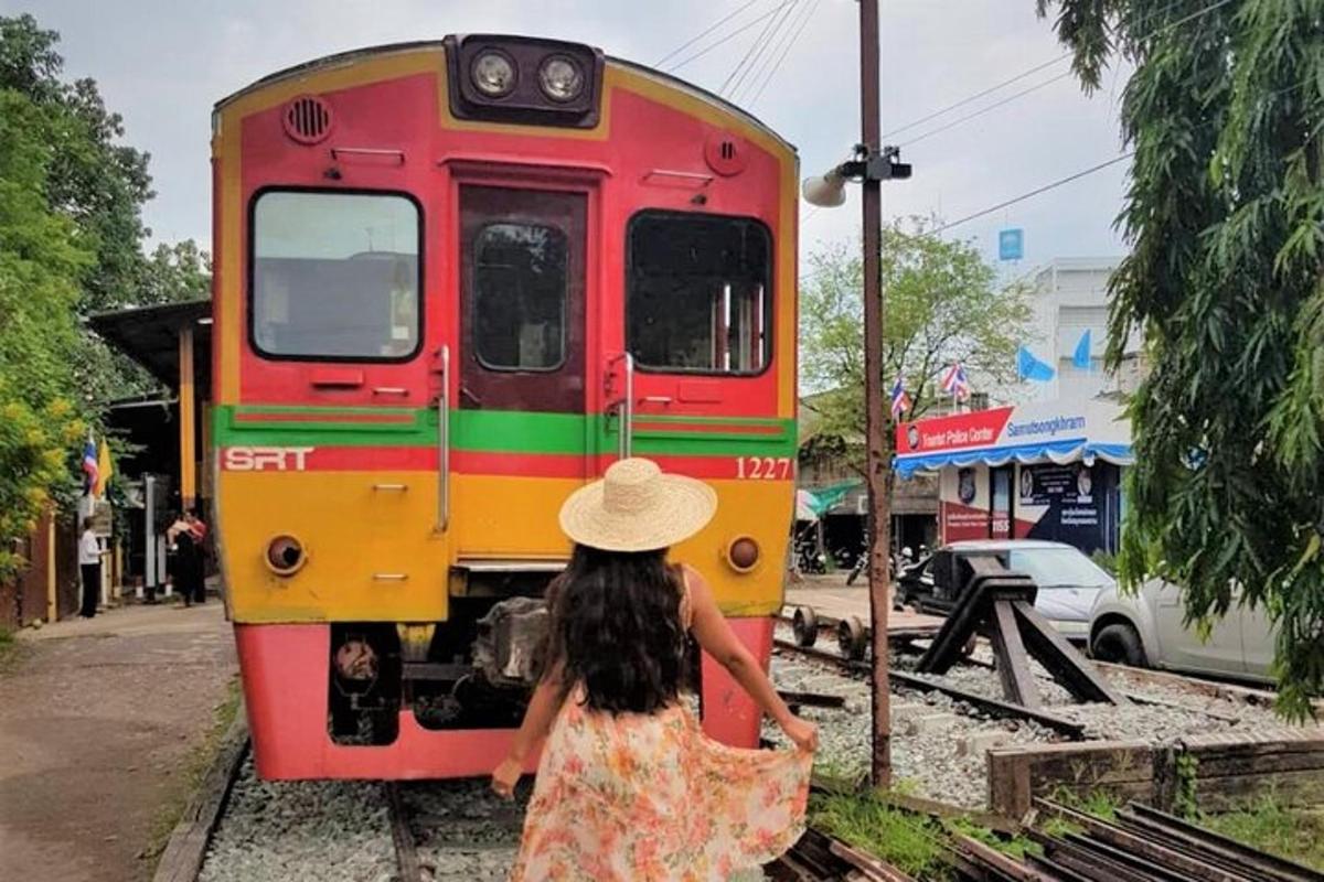 una dona caminant cap a un tren vermell i groc