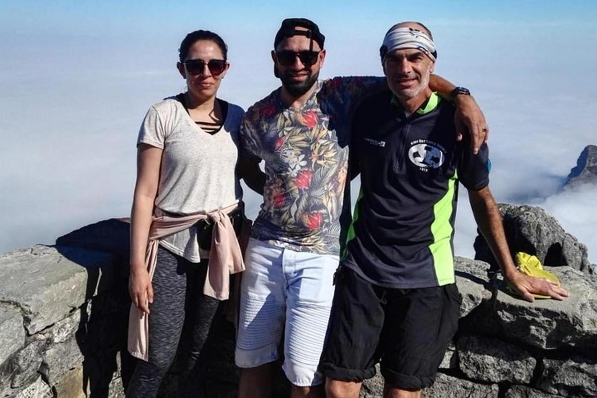 tre persone in piedi sulla cima di una montagna