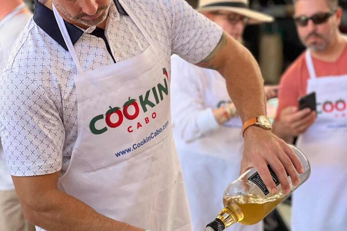 un home amb un davantal blanc que sosté una ampolla de cervesa