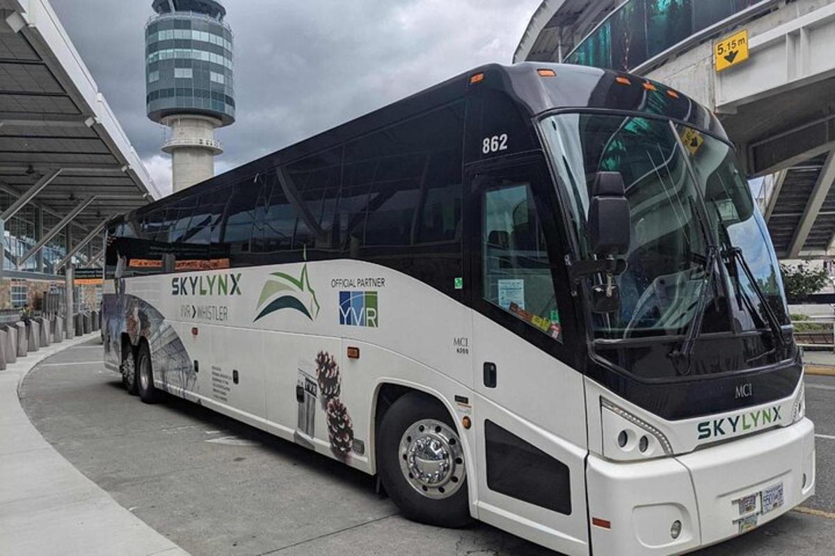 um grande ônibus branco estacionado ao lado de um prédio