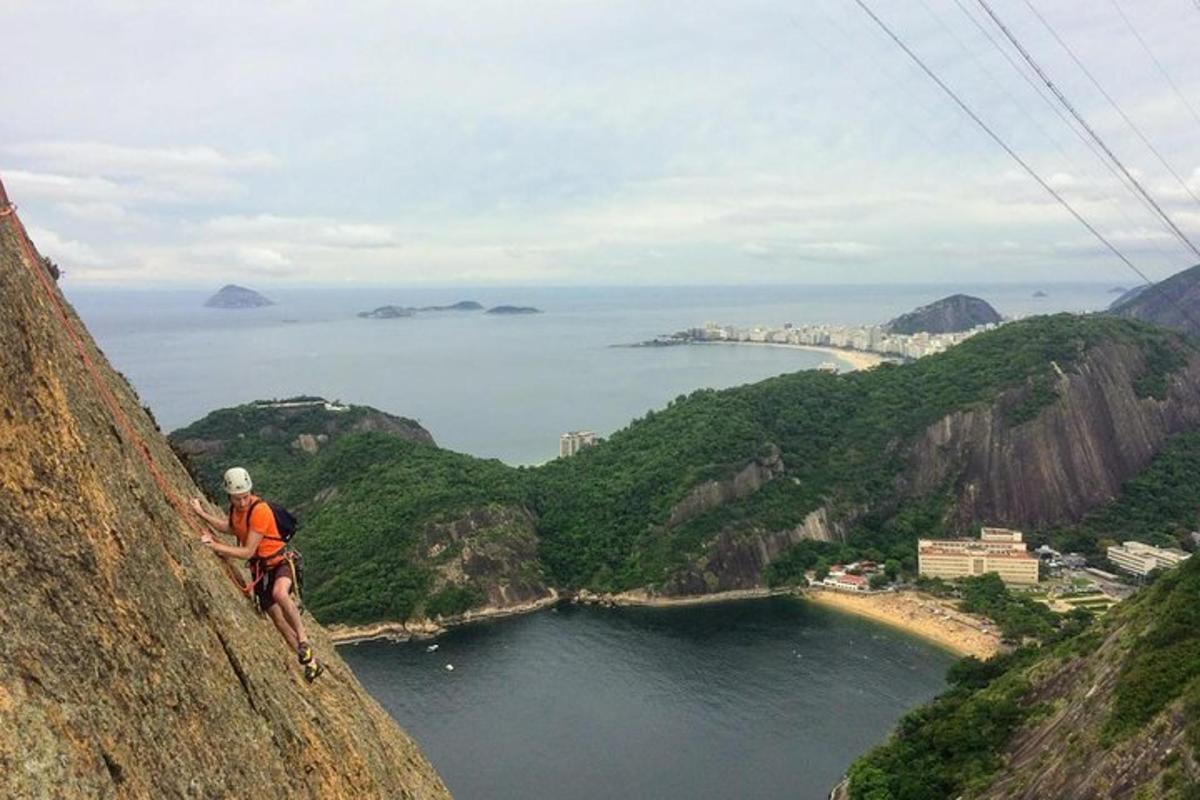 um homem em pé no topo de uma montanha com vista para um corpo d'água