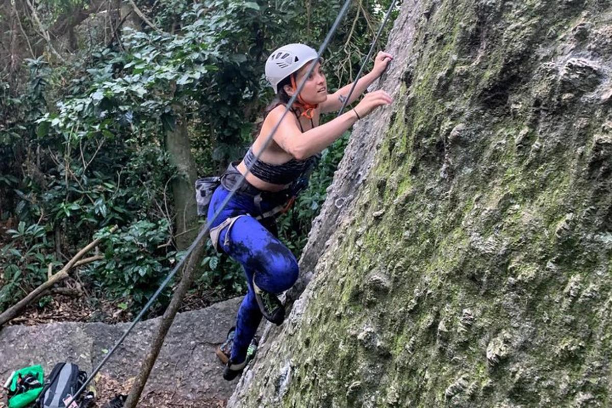 uma mulher de capacete escalando uma parede de rocha