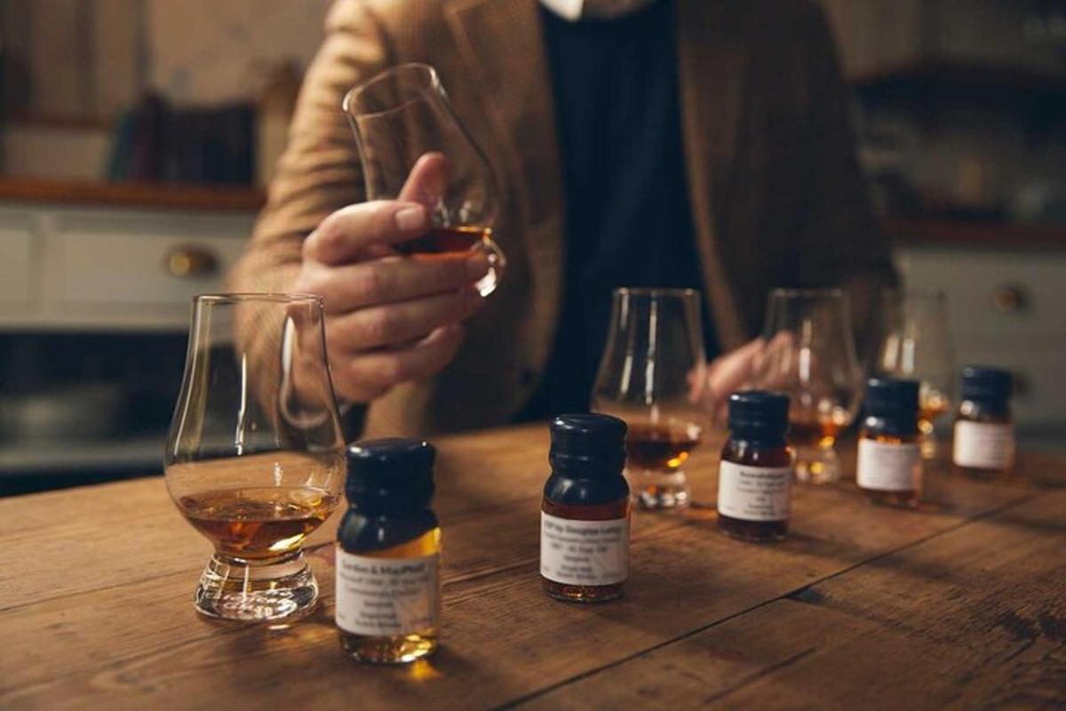 un uomo che tiene in mano un bicchiere di vino accanto a bottiglie di whisky