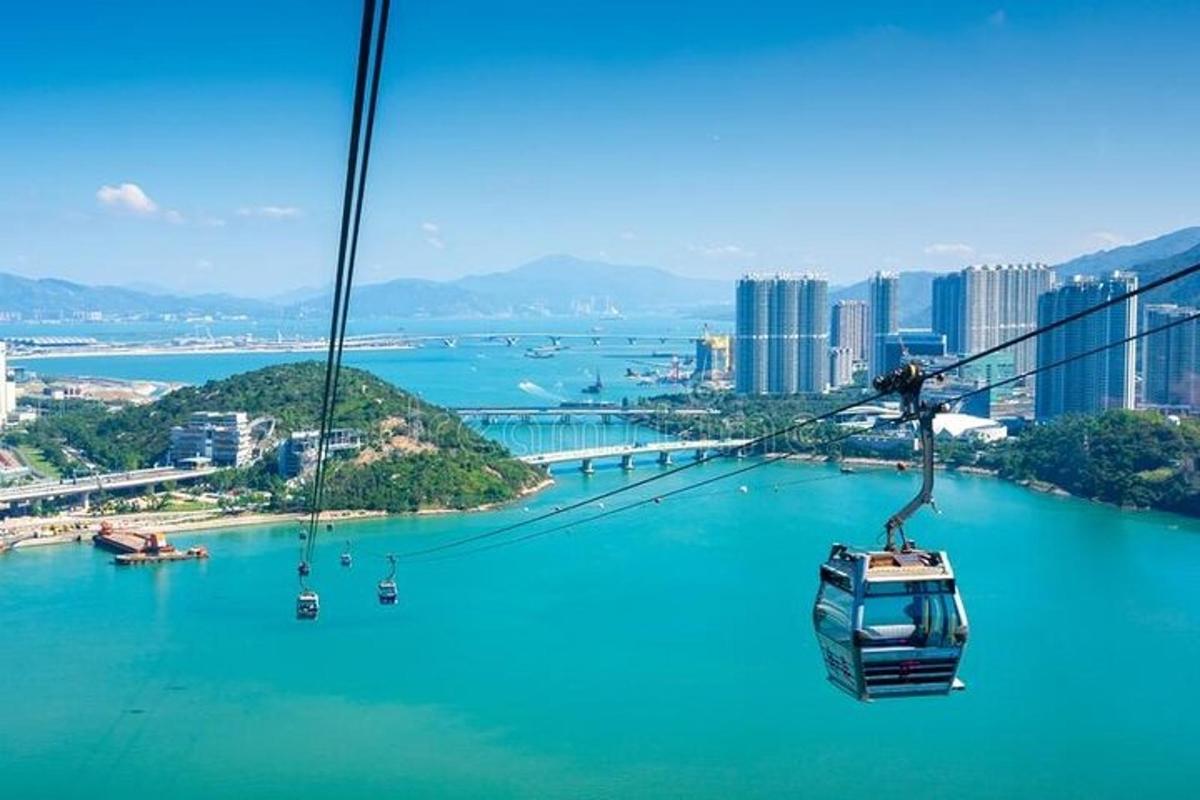 a gondola flying over a blue river with a city