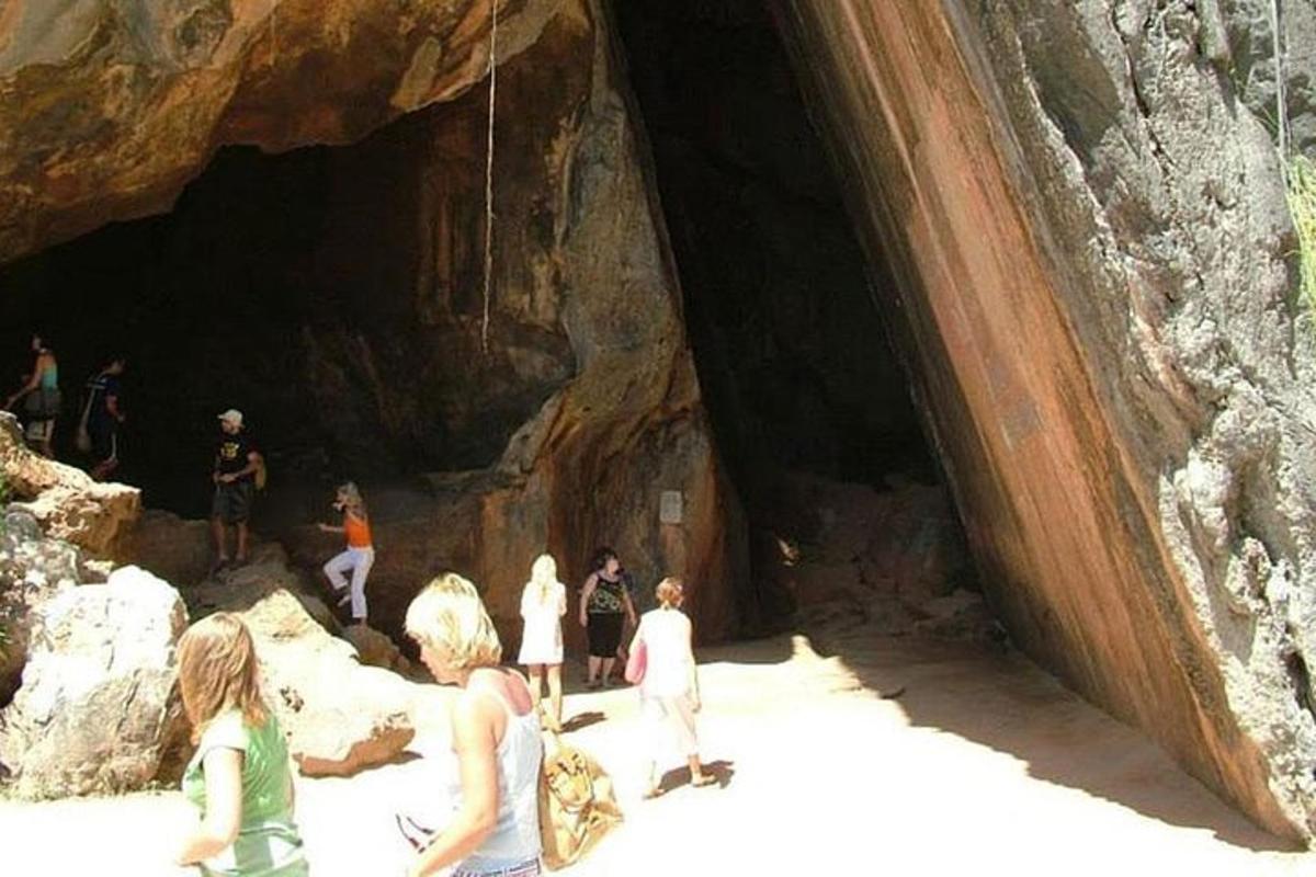 um grupo de pessoas em pé em frente a uma caverna