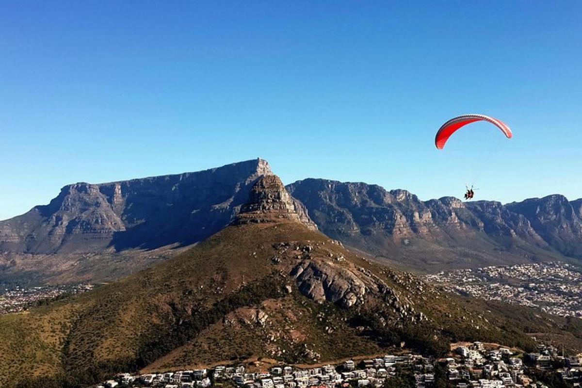 una persona fent volar un estel al cim d'una muntanya