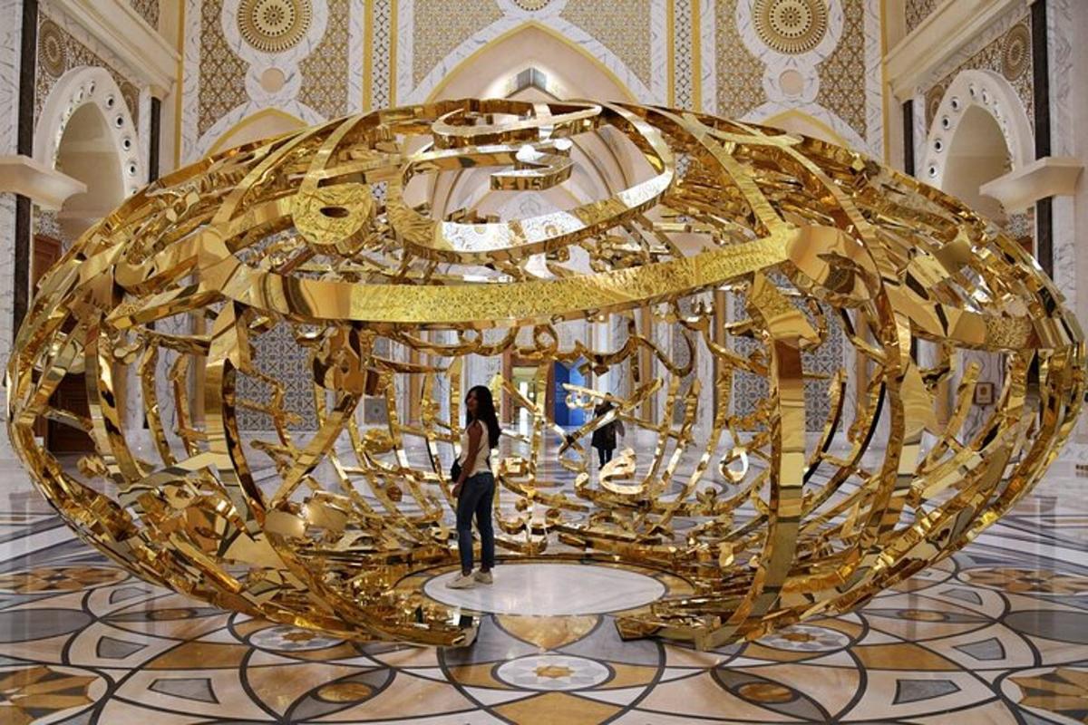 a woman standing in front of a large gold sculpture