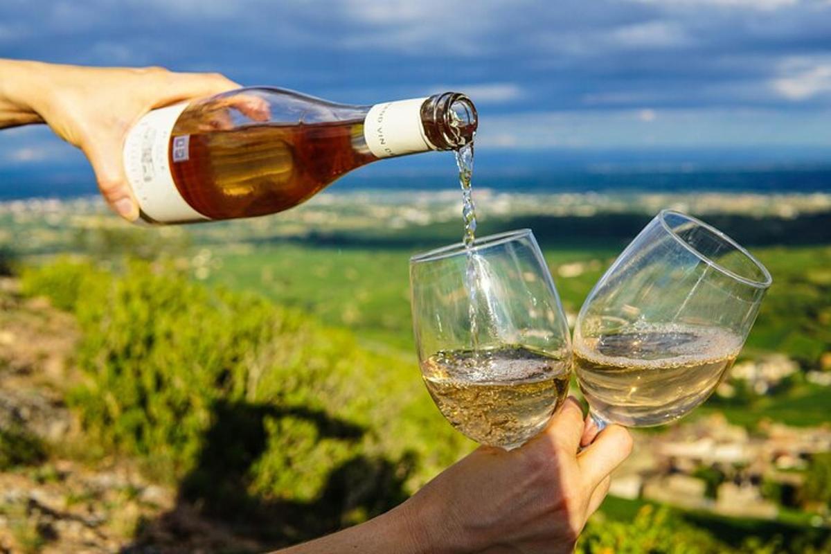 uma pessoa despejando vinho branco em duas taças de vinho