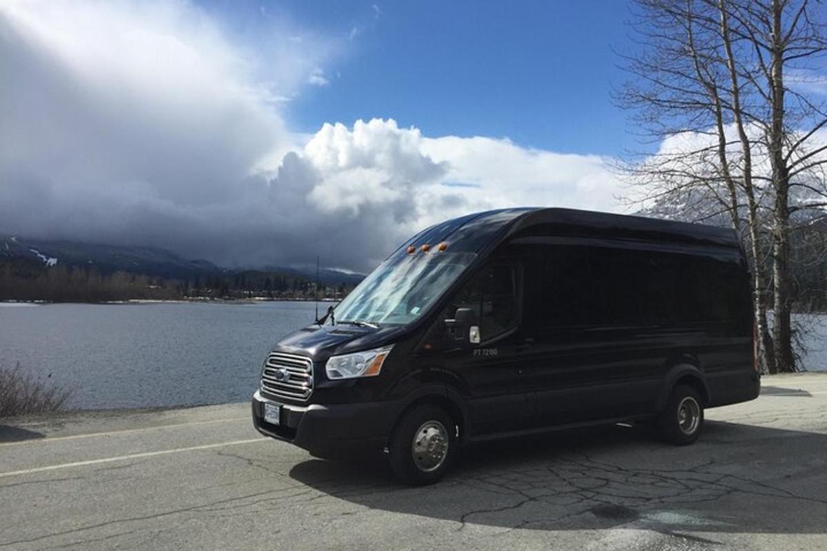 a black van parked in a parking lot next to a lake