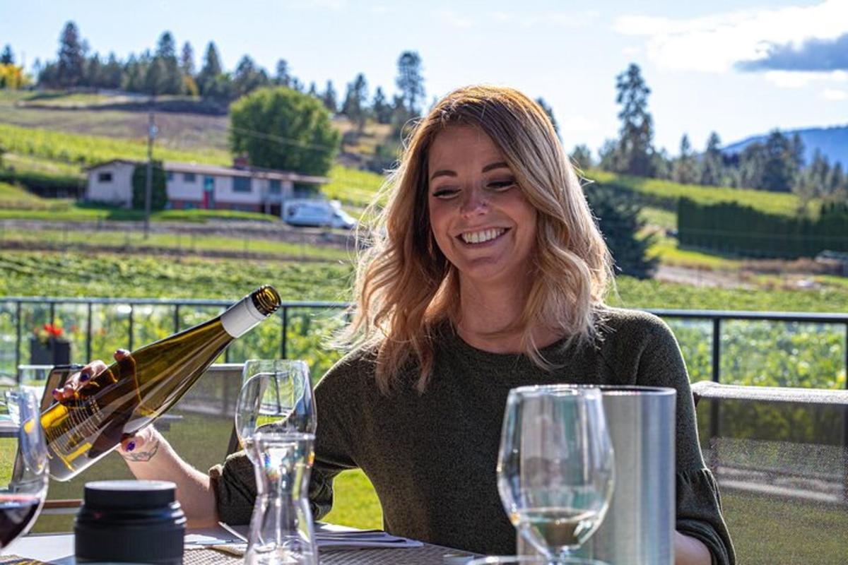 a woman sitting at a table pouring a bottle of wine