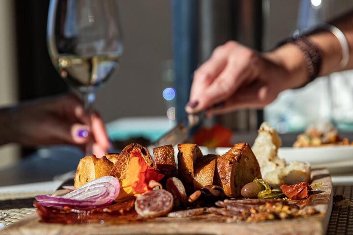 a person preparing a plate of food with a glass of wine
