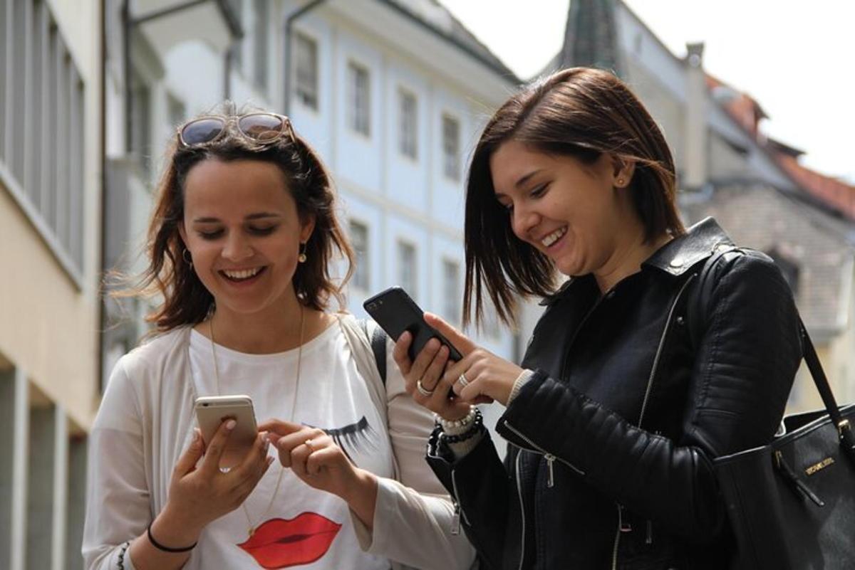dvě ženy se smějí a dívají se do svých mobilních telefonů