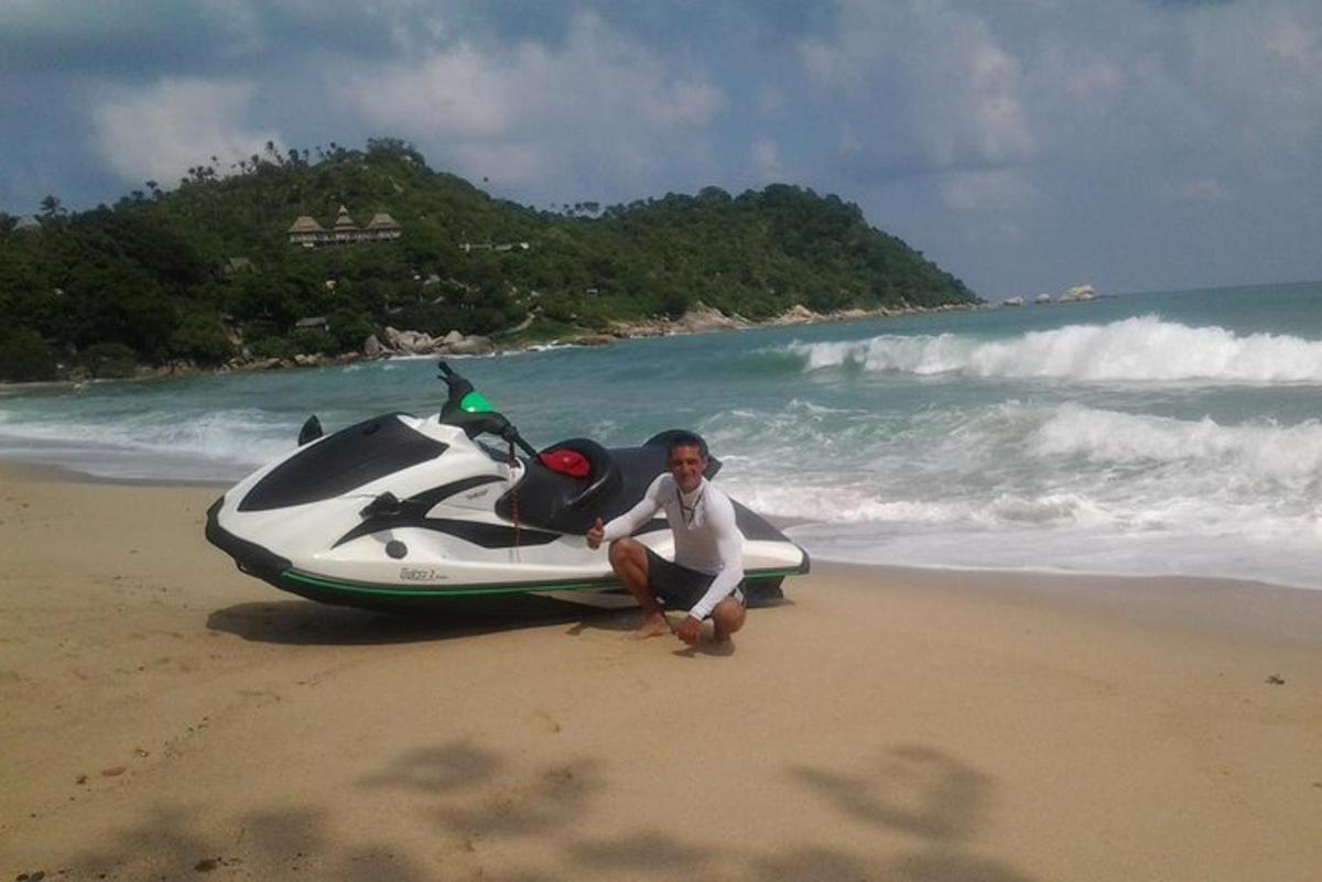 moški kleči poleg motorja na plaži