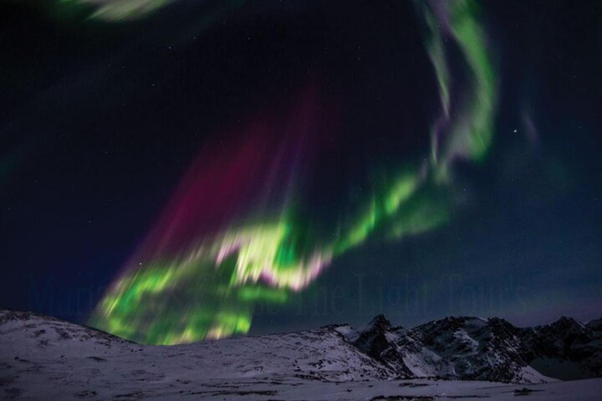una aurora al cel sobre una muntanya coberta de neu