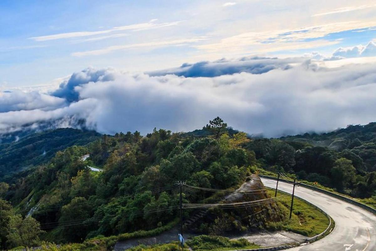 una strada tortuosa in cima a una montagna con nuvole