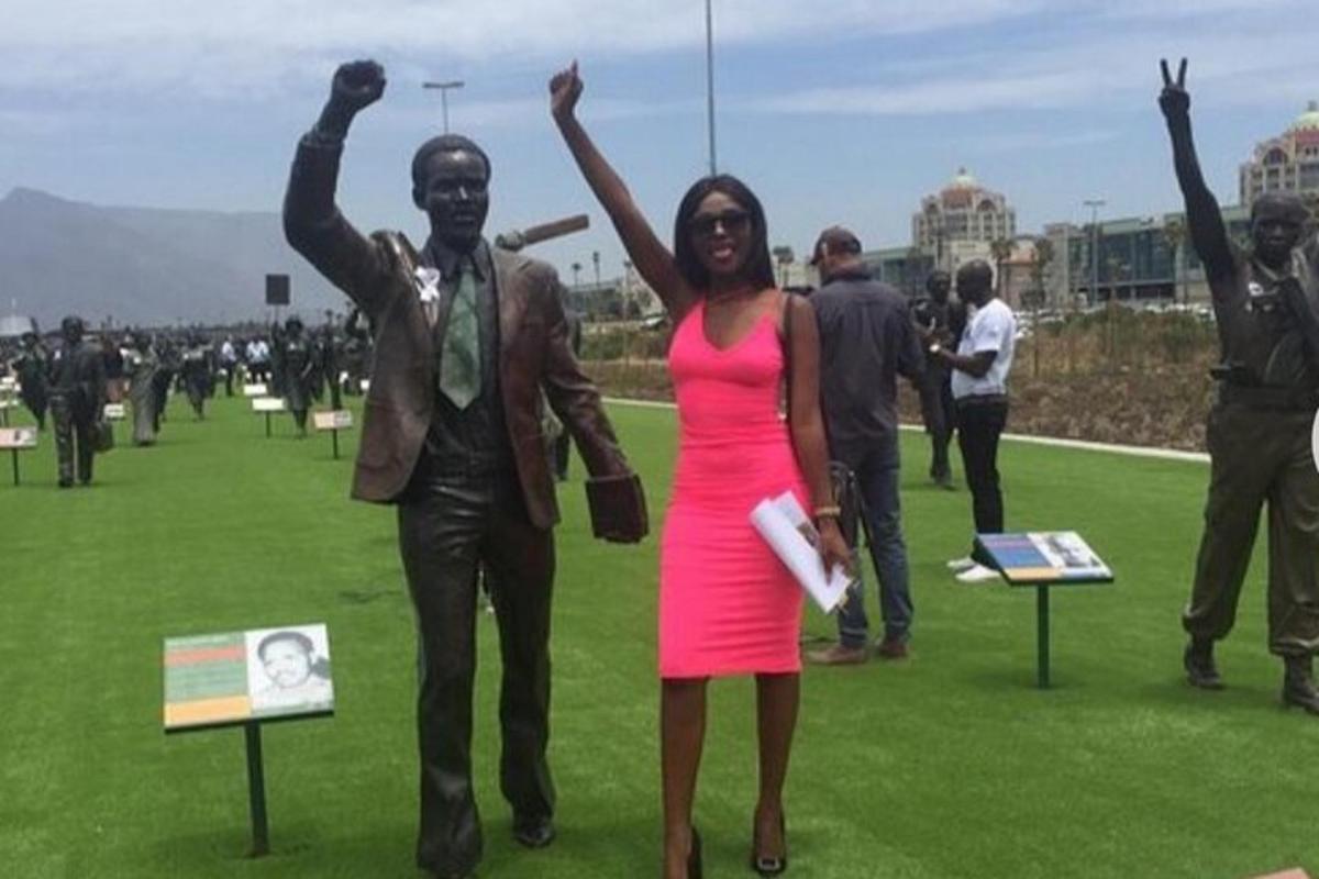 una donna in un vestito rosa in piedi accanto a una statua