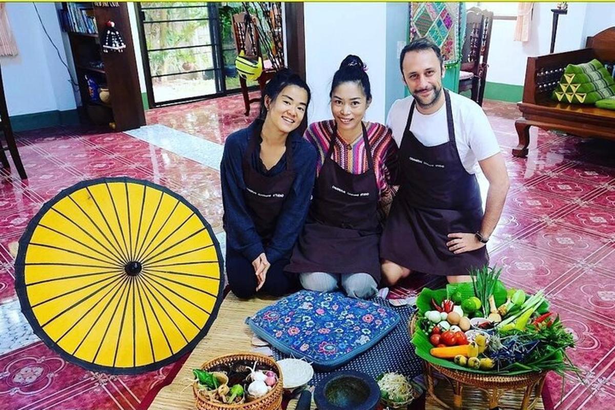 three people posing for a picture next to a table of food