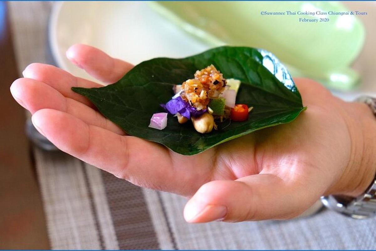 a hand holding a green leaf with food on it