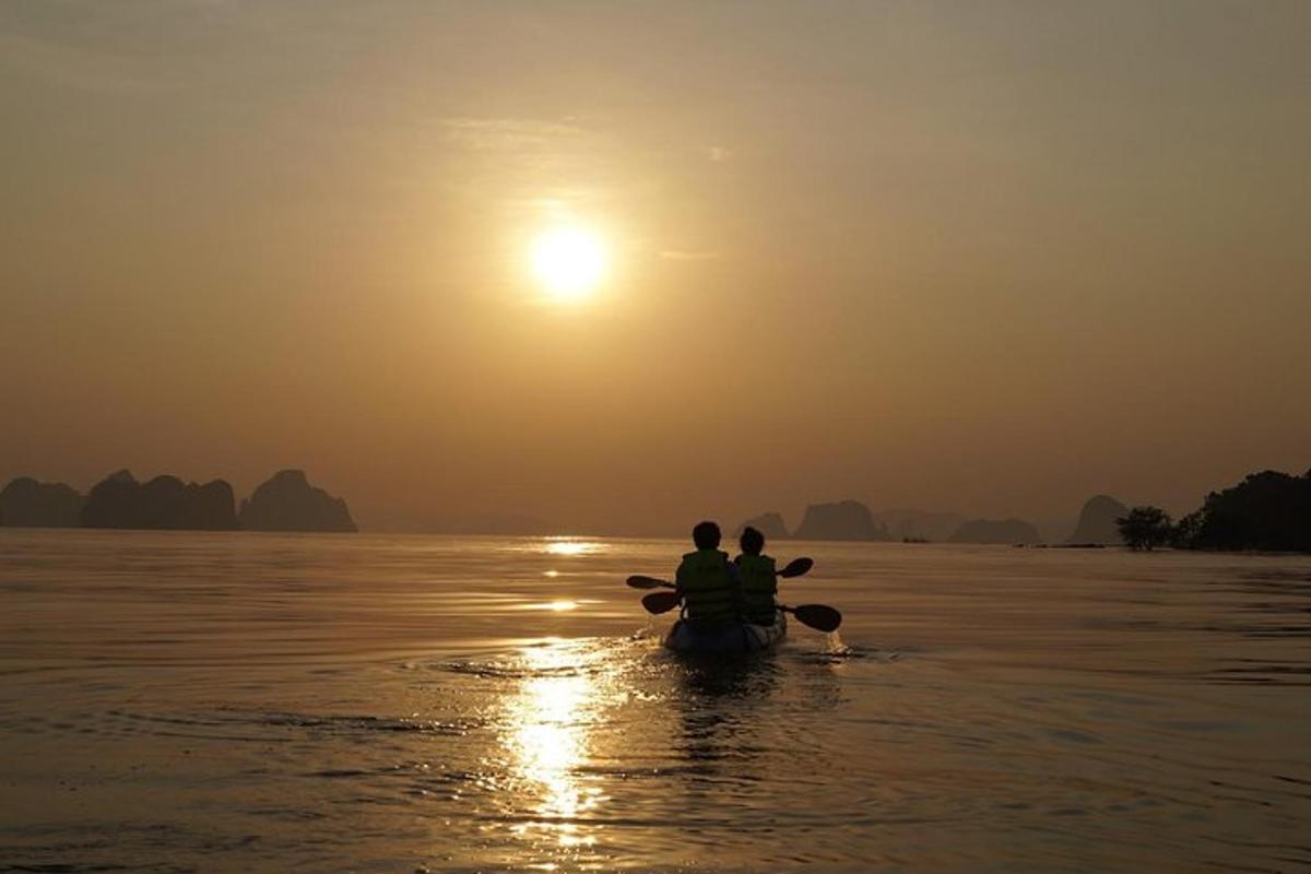 duas pessoas em um barco na água ao pôr do sol