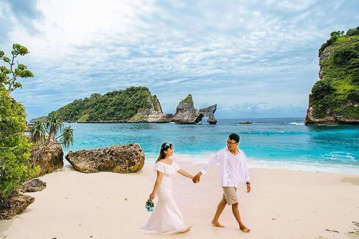 Una novia y un novio caminando por una playa