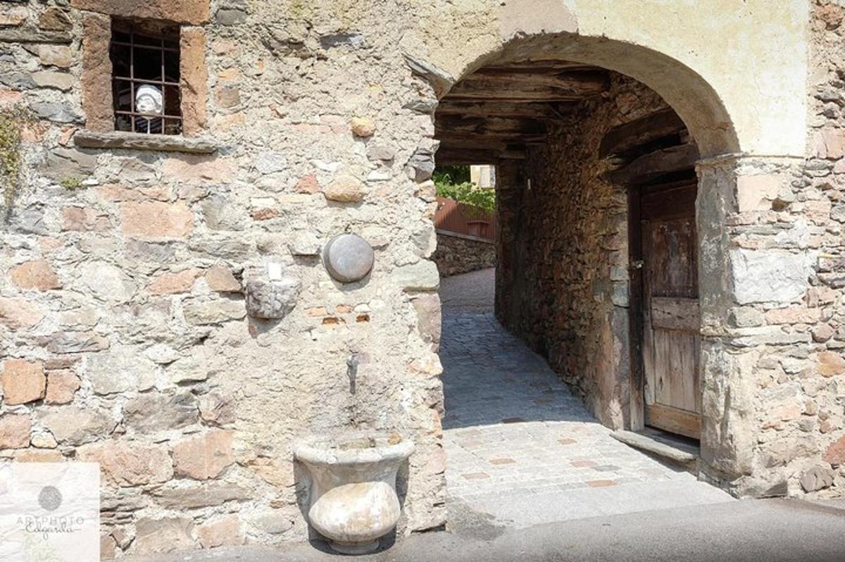 a stone building with a door and a dog in a window